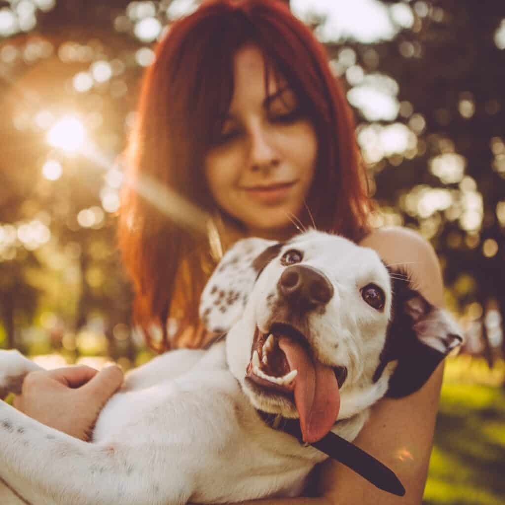 Young woman holding her dog in nature